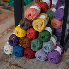 A stack of colourful yarns by Jamieson & Smith on a wooden table at Stag & Bow haberdashery London