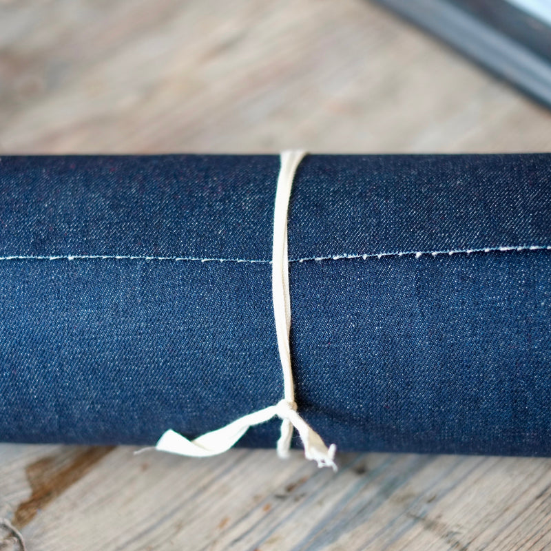 Blue Denim fabric rolled up on a wooden table at Stag & Bow haberdashery London